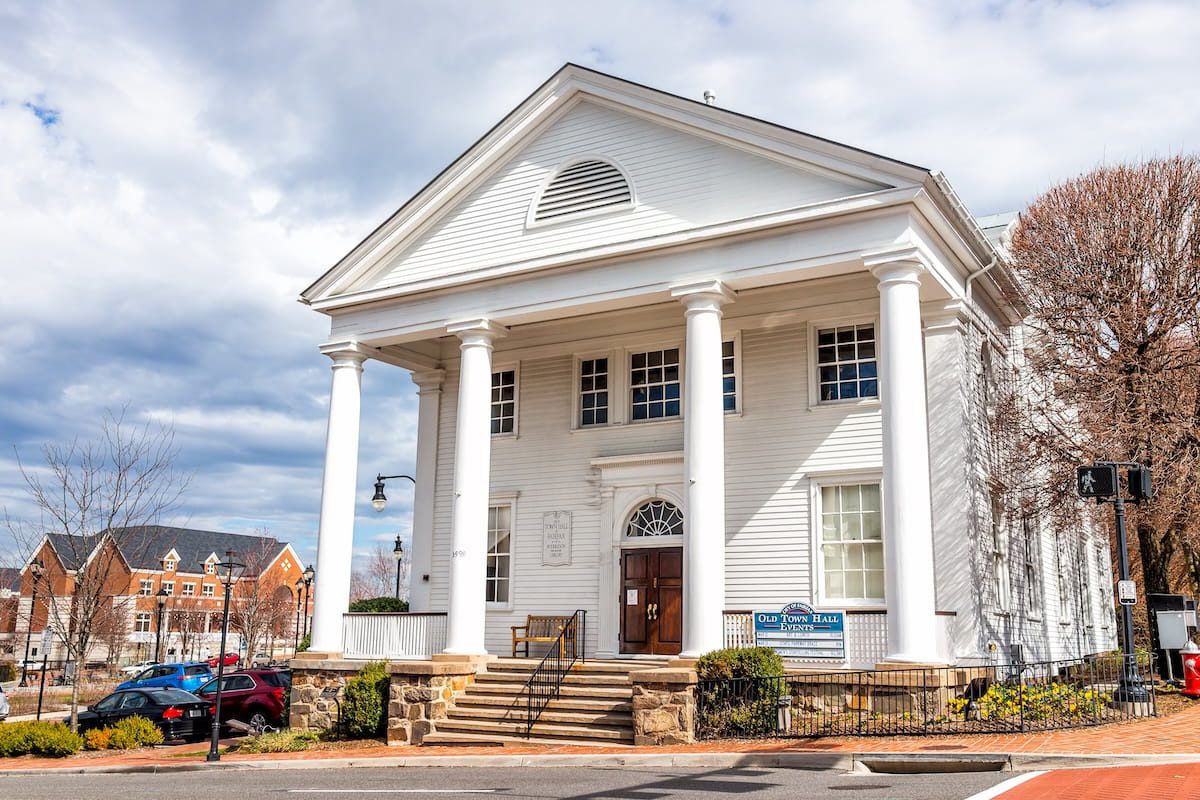 City-of-Fairfax-USA-Old-town-hall-colonial-architecture-with-sign-for-Huddleson-Memorial-public-library-community-events-in-downtown-at-University-drive-in-Fairfax-county-Virginia